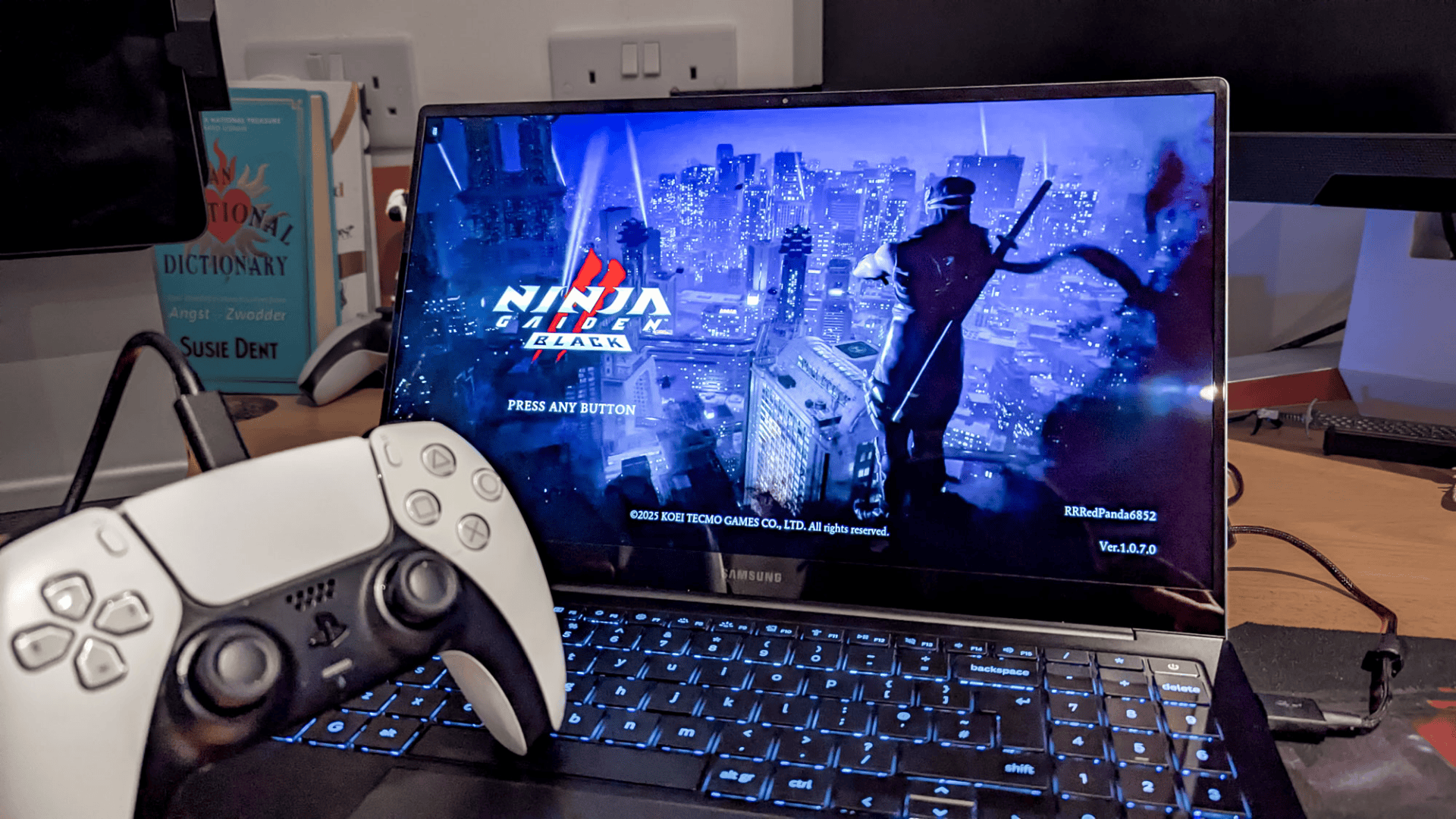 a chromebook on a desk displaying an action game start screen with a white game controller in the foreground