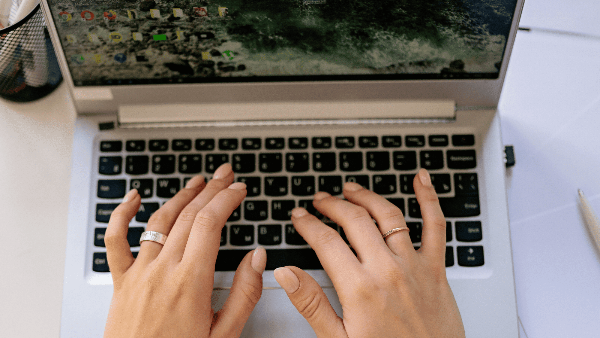 a pair of hand typing on a classic laptop on a desk