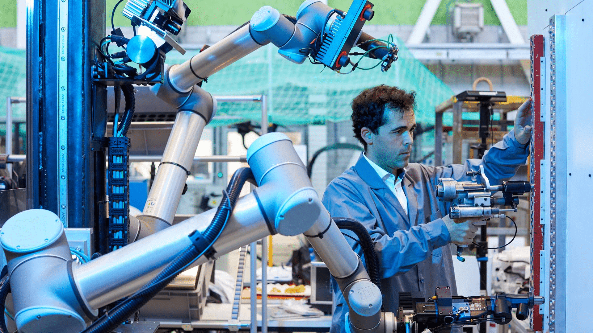 a technician works alongside a robotic arm in a modern factory highlighting robotics and automation in action