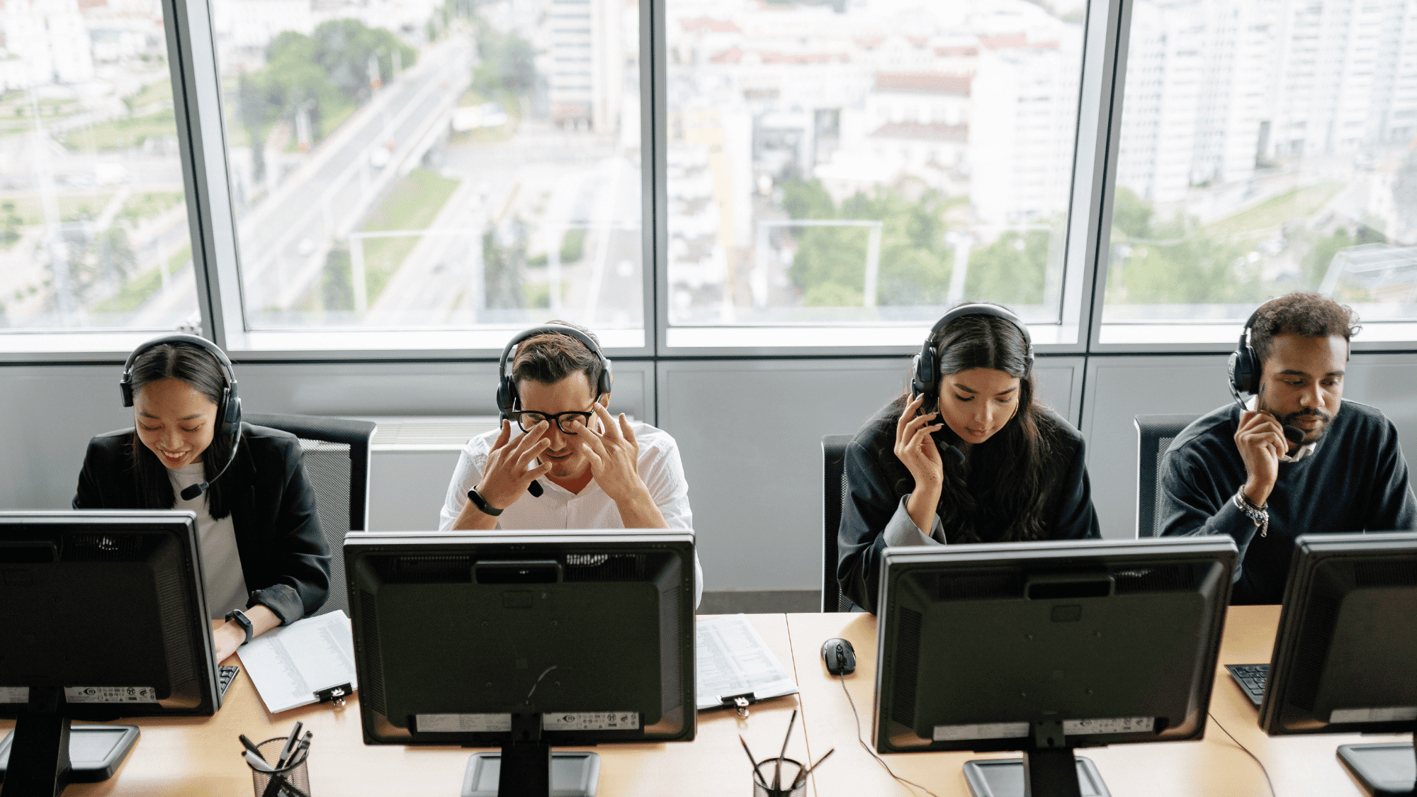 four cybersecurity professionals work in a modern office with headsets, focused on their tasks at computer stations