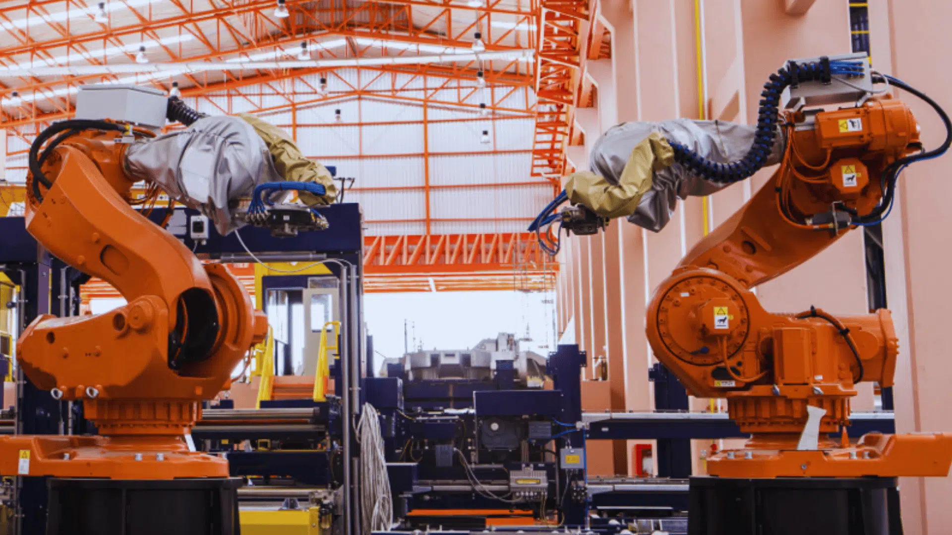 orange industrial robotic arms operating inside modern factory facility