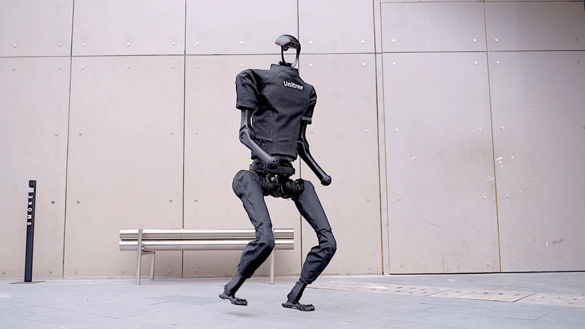 unitree humanoid robot in black outfit walking outdoors