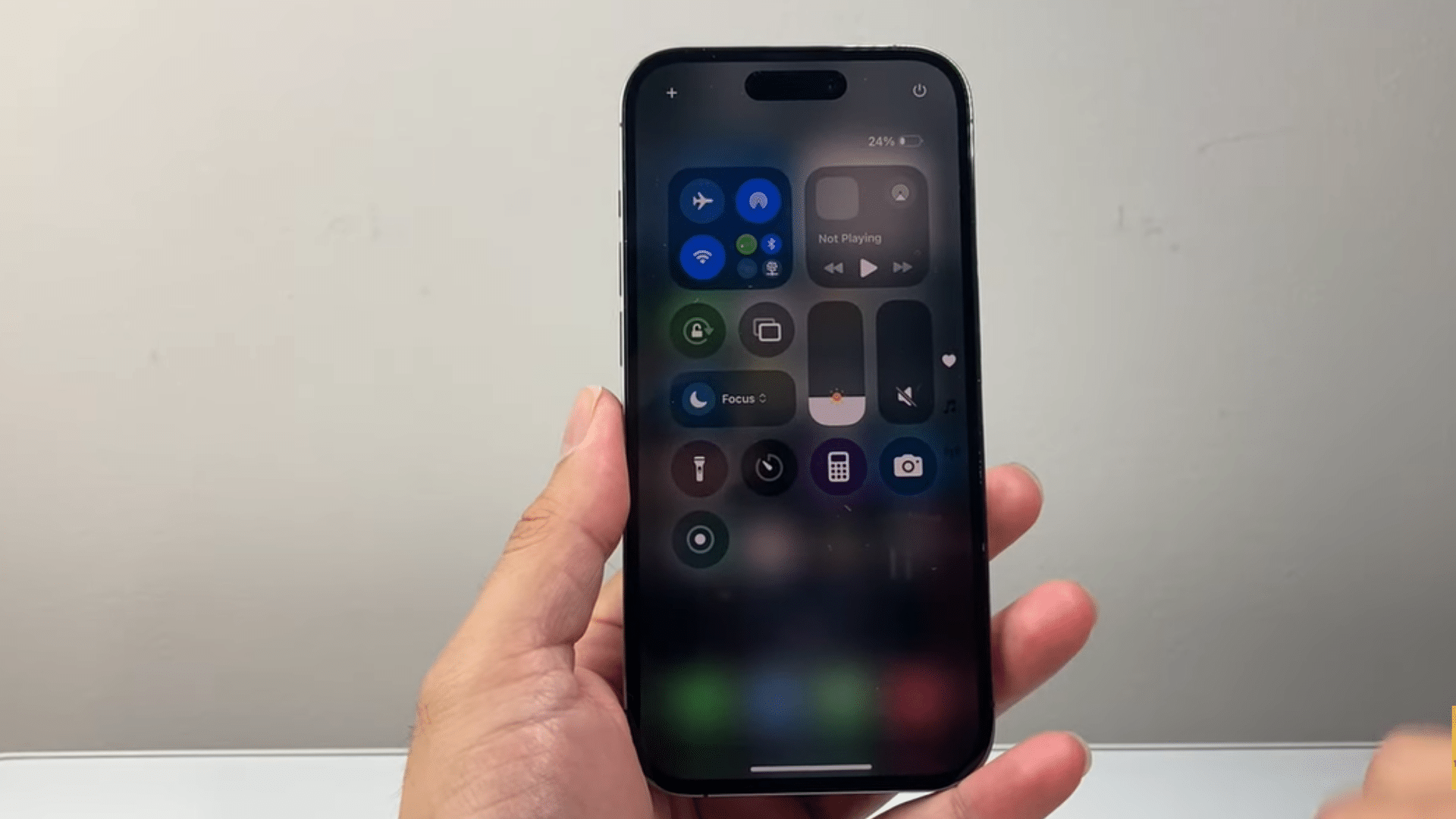 a hand holding an iphone displaying control center settings with wifi and cellular data control on screen