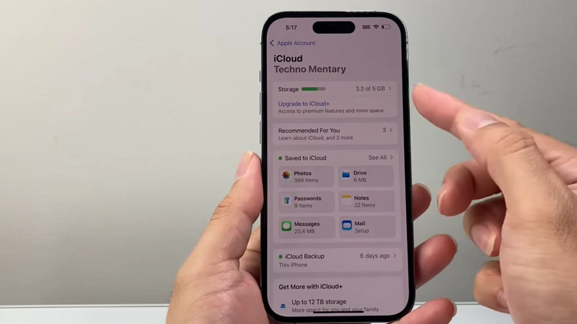 a hand holding an iphone displaying icloud storage details with apps and backup usage information on screen