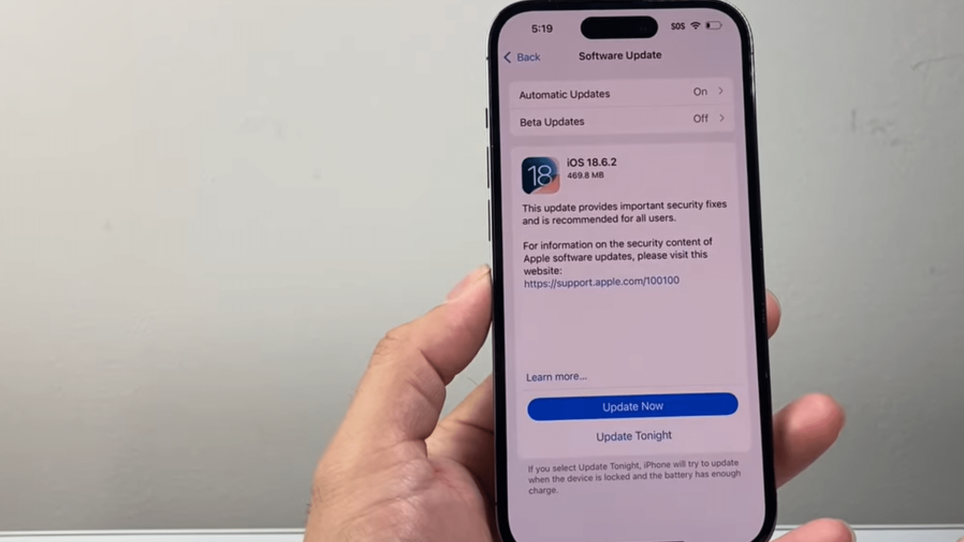 a hand holding an iphone displaying the software update screen with ios update options and update now button