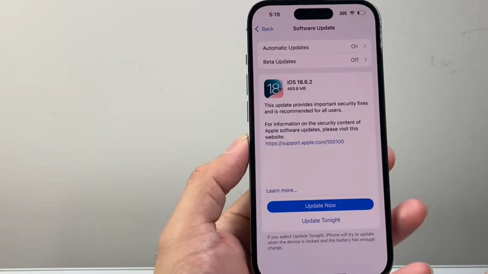 a hand holding an iphone displaying the software update screen with ios update options and update now button