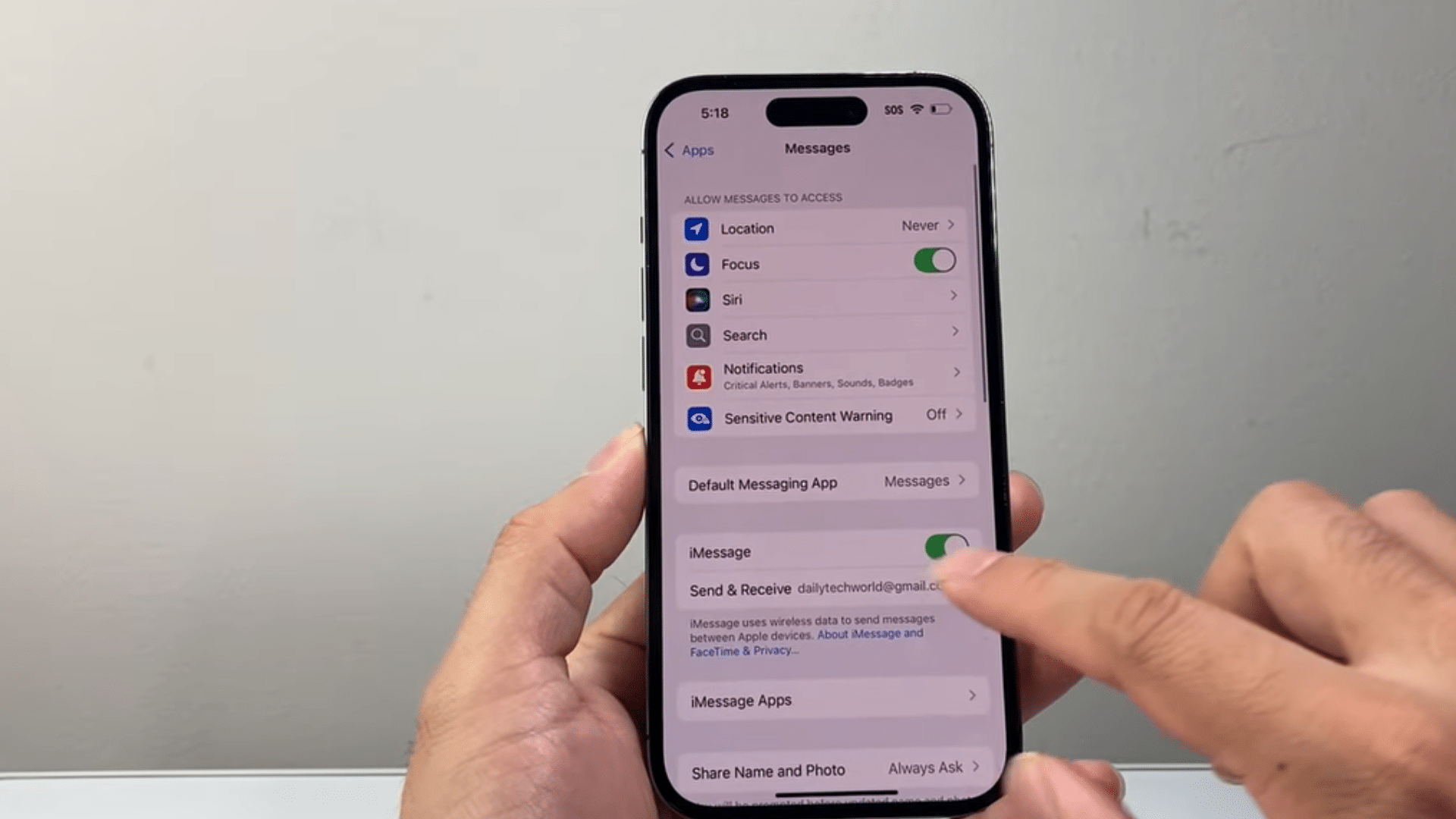 a hand holding an iphone showing messages settings while toggling the imessage switch on and off on screen