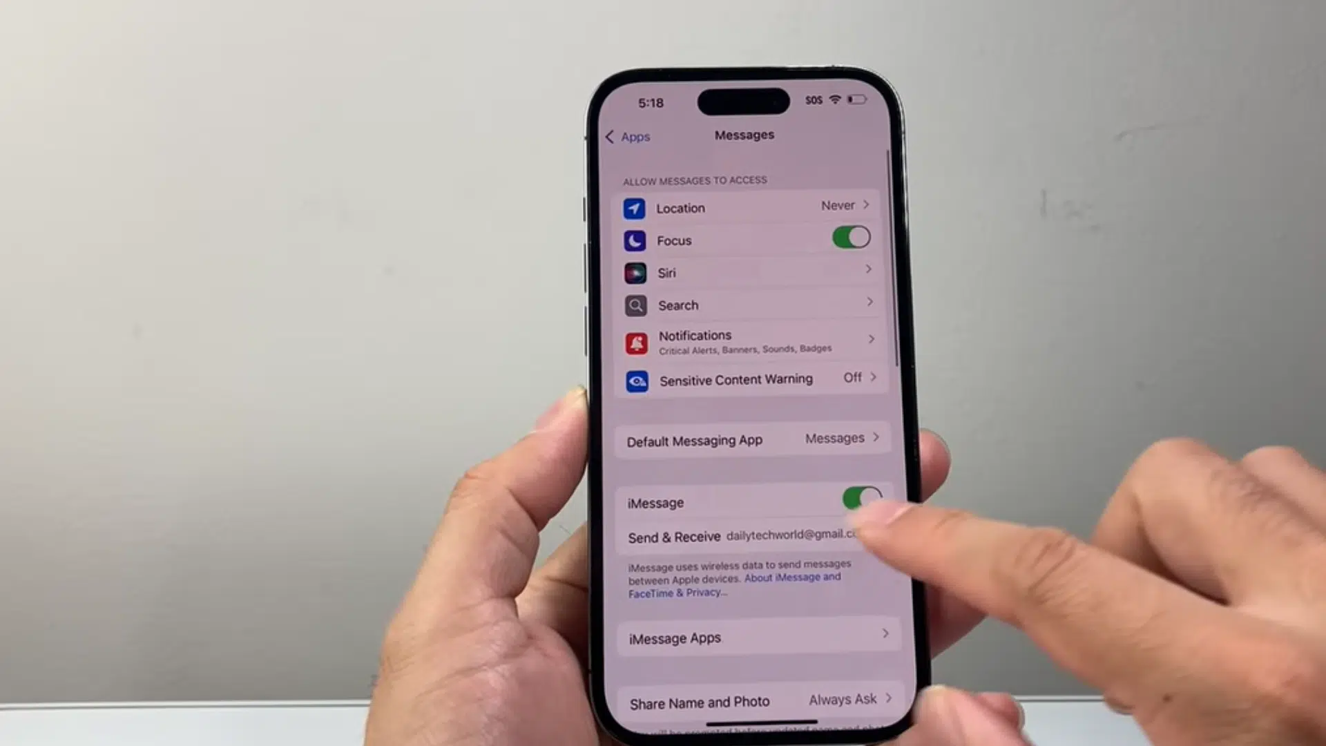 a hand holding an iphone showing messages settings while toggling the imessage switch on and off on screen