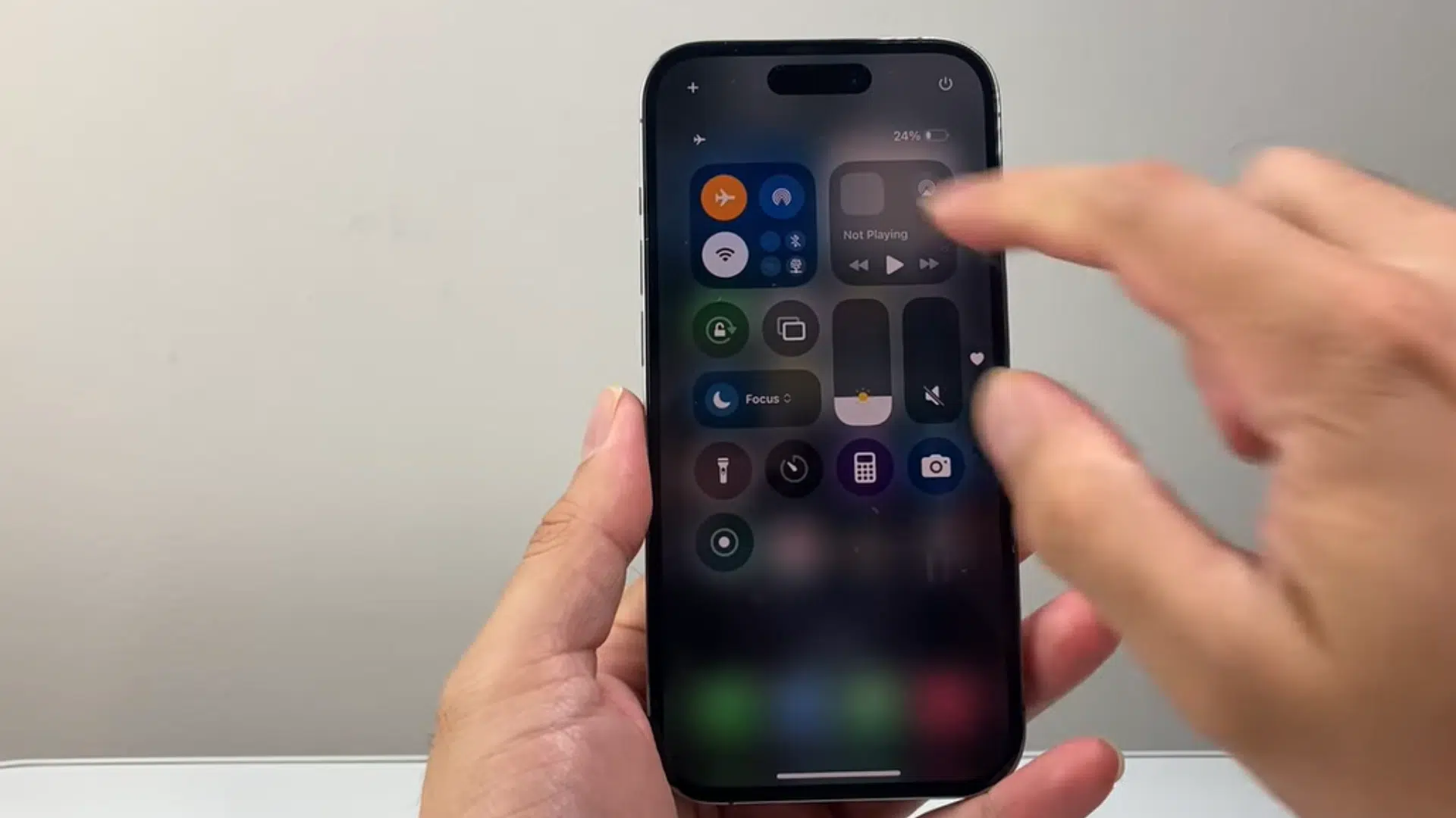a hand holding an iphone with airplane mode enabled in control center while another hand taps the screen