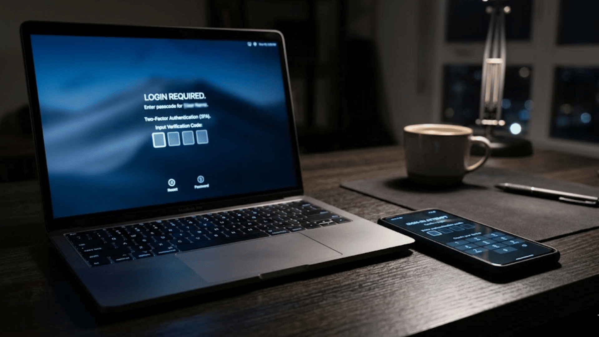 a laptop and smartphone on desk display login required screen with two factor authentication prompt and code entry fields at night