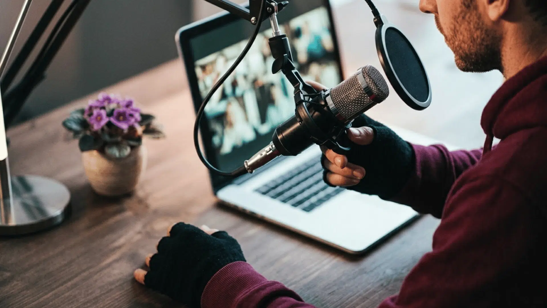 man recording a tech podcast with a microphone beside a laptop in a home studio setup