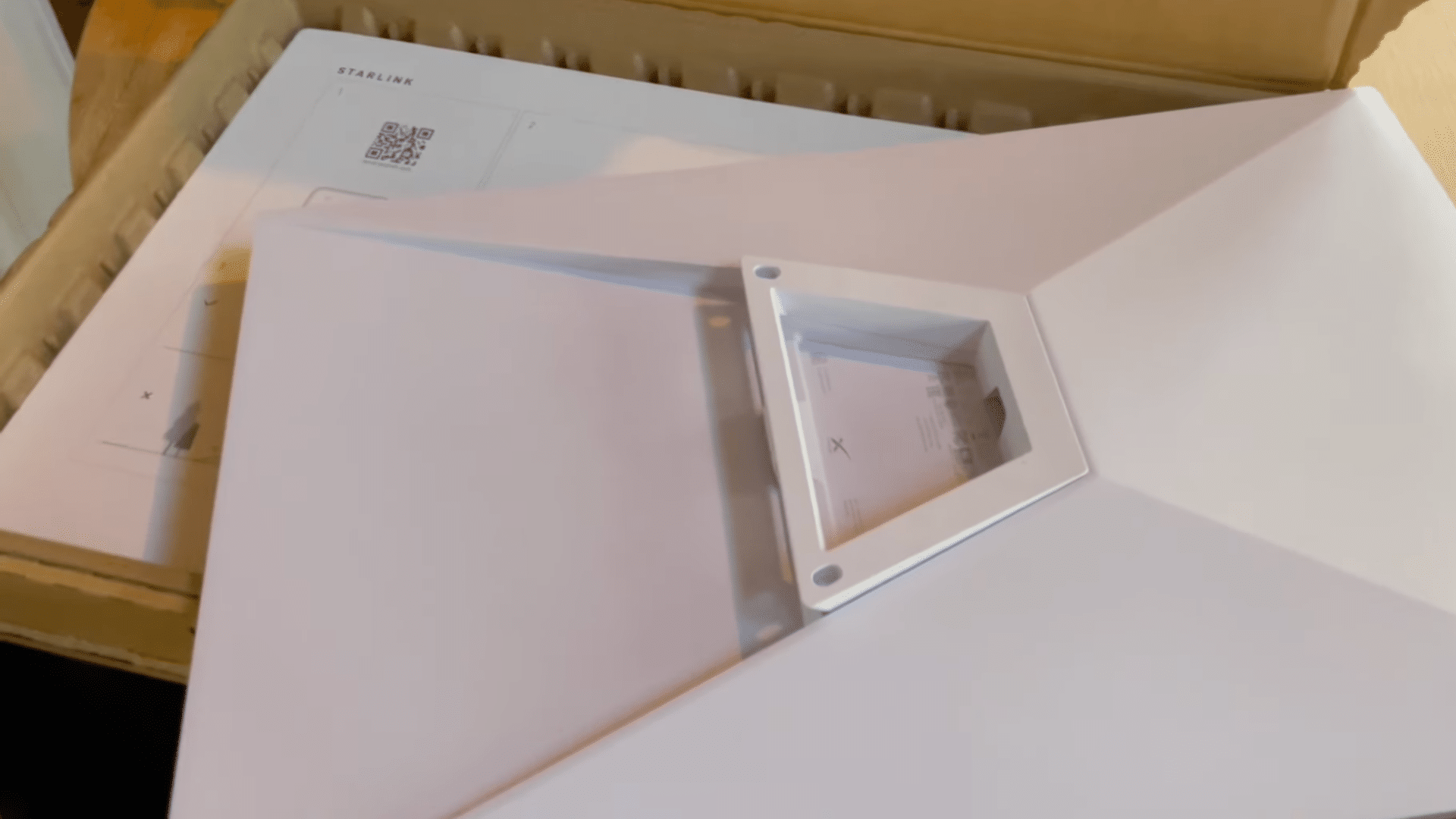open starlink box with white mounting panel and setup guide placed inside packaging