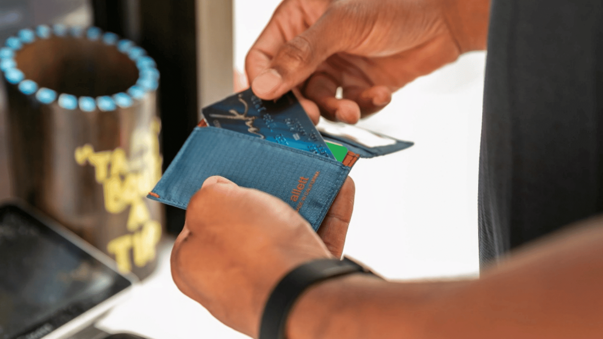 person holding an rfid blocking wallet while using contactless payment cards near a payment terminal (1)
