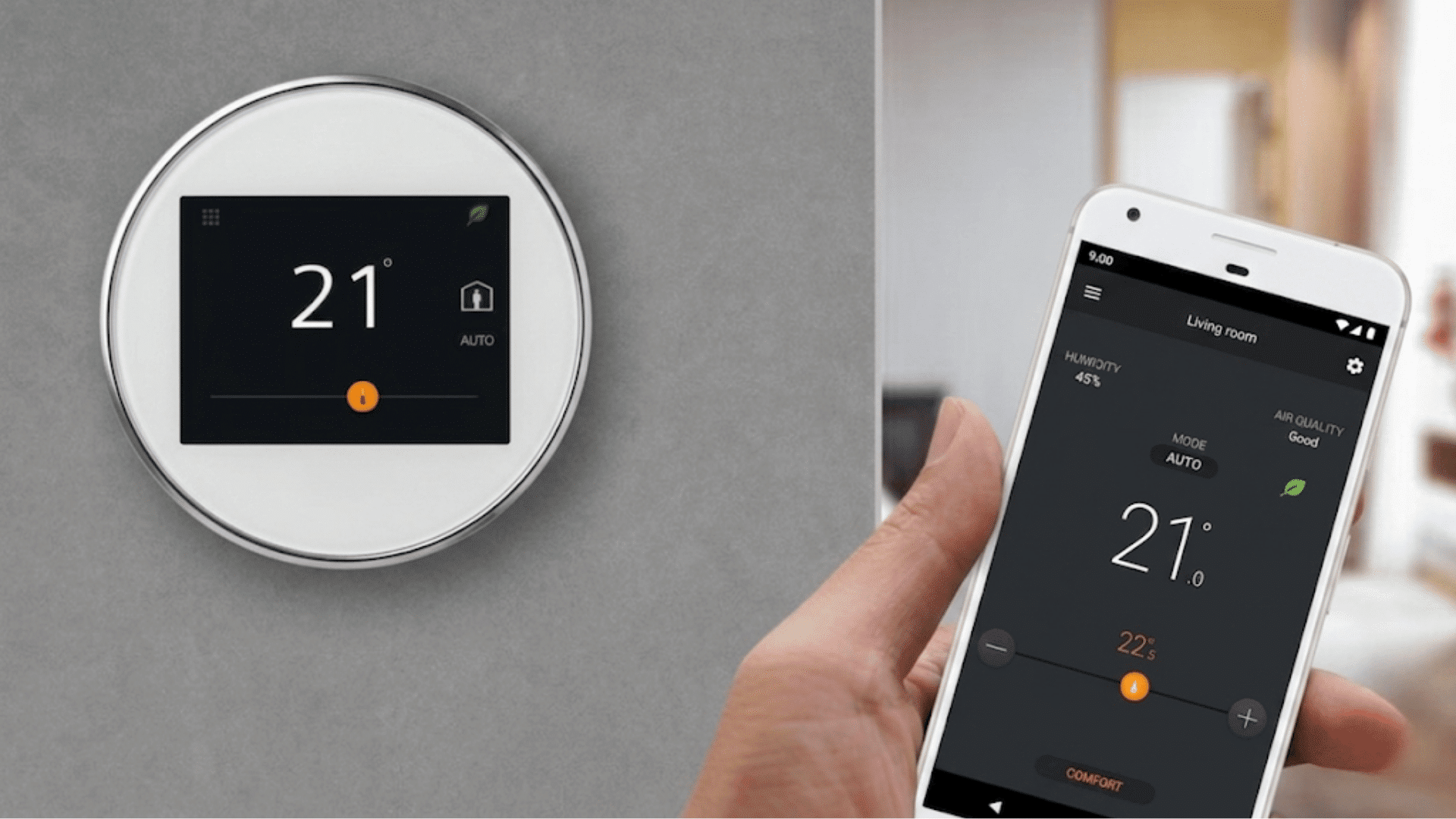 smart thermostat mounted on a wall beside a person holding a smartphone app showing temperature controls indoors