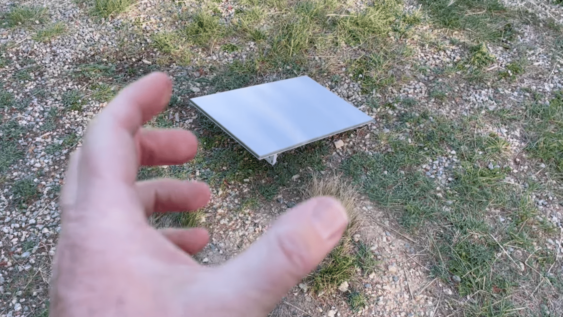 starlink dish placed on open ground in a clear outdoor area with grass and gravel around it