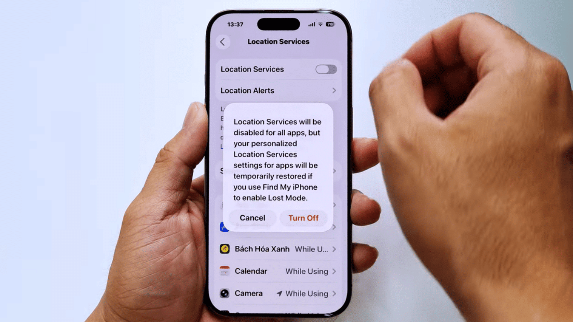 hands holding an iphone showing a location services disable confirmation popup with cancel and turn off options