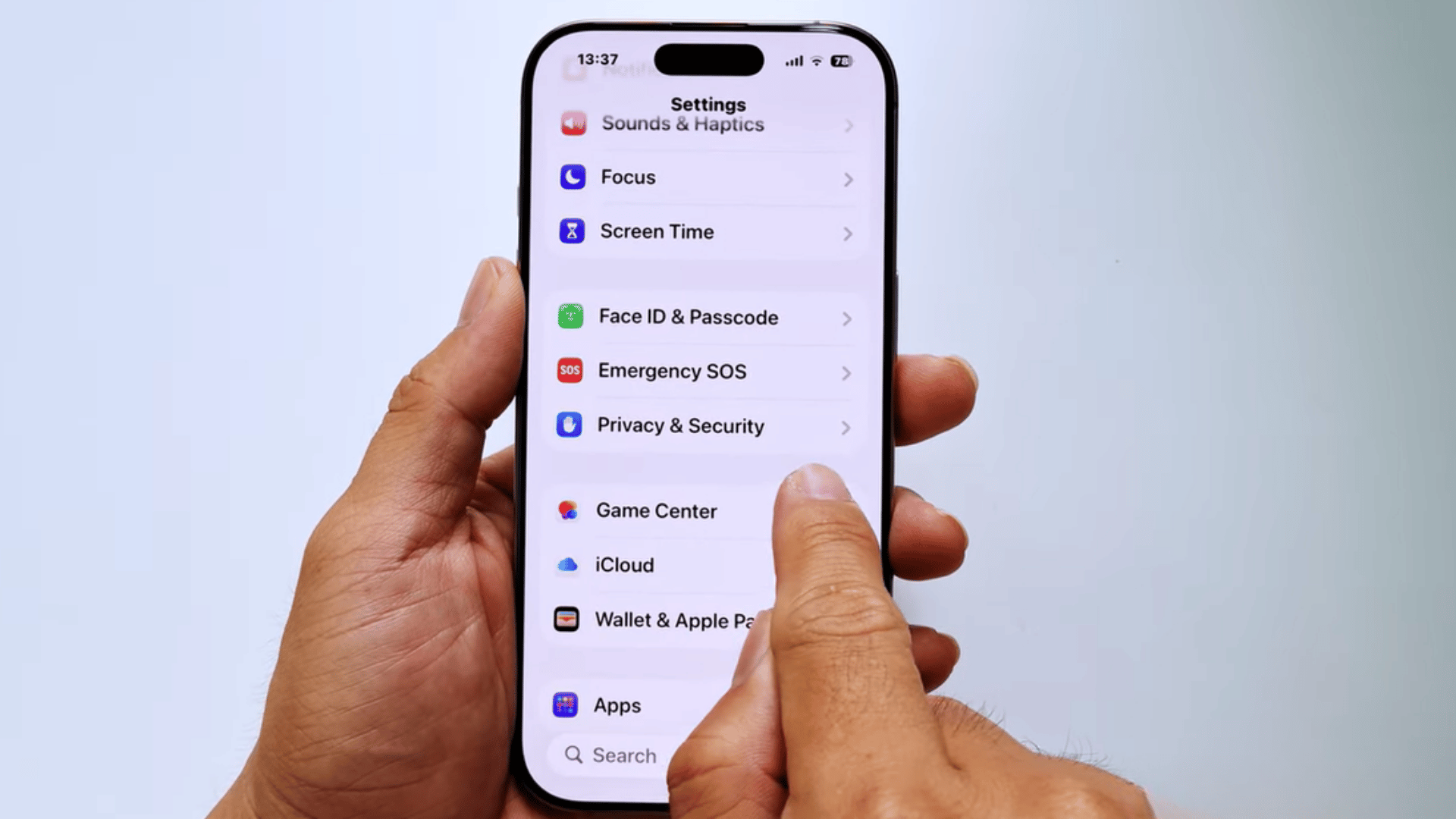 hands holding an iphone showing privacy and security settings while a finger taps the menu on the screen in settings app