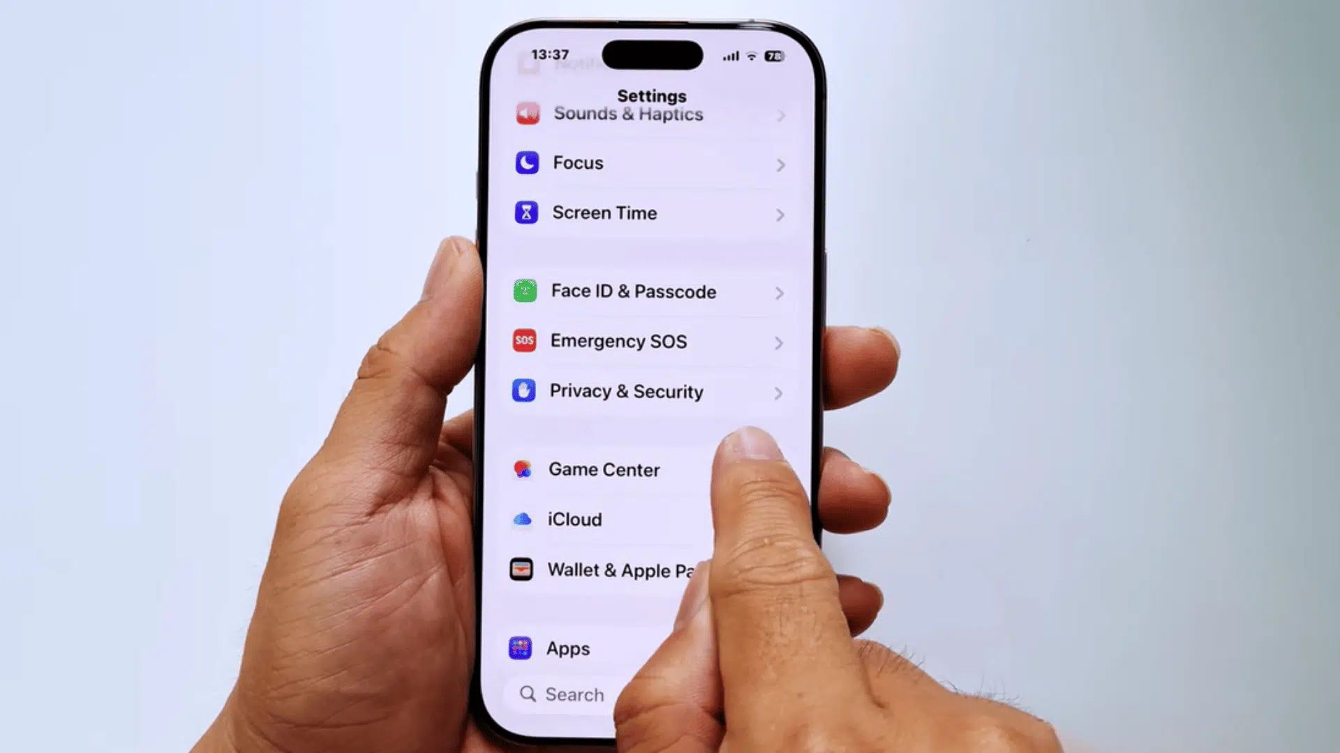 hands holding an iphone showing privacy and security settings while a finger taps the menu on the screen in settings app