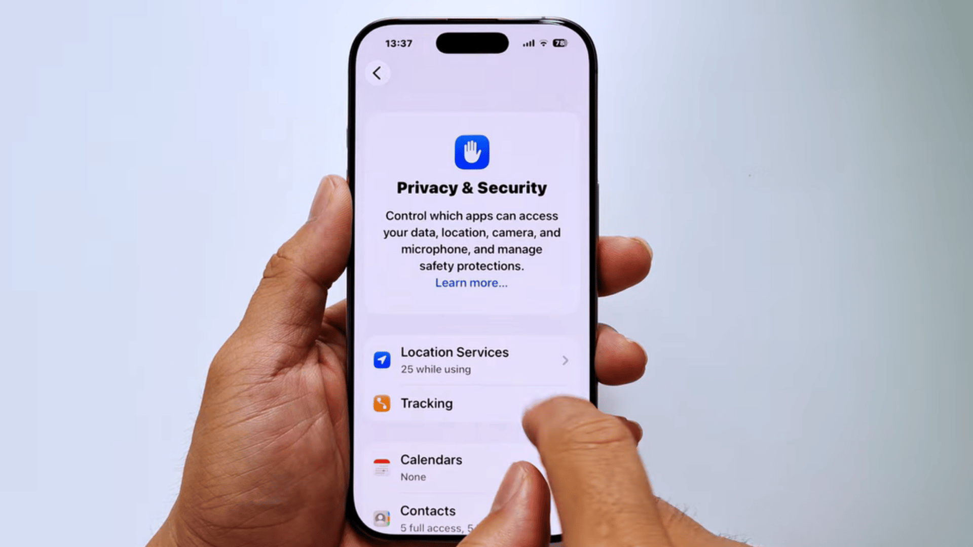 hands holding an iphone showing privacy and security settings while scrolling through app permissions and controls