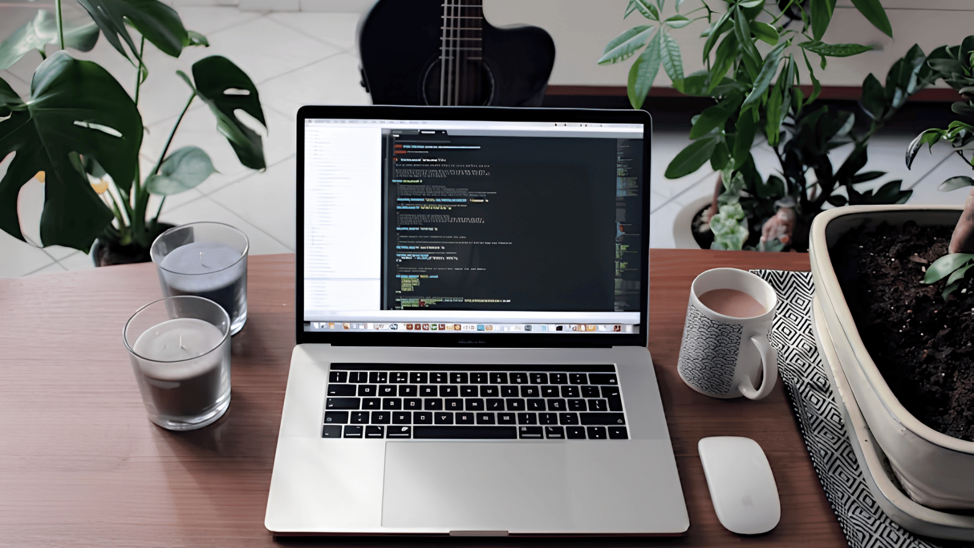 laptop showing code on a wooden desk with plants coffee mouse and guitar nearby