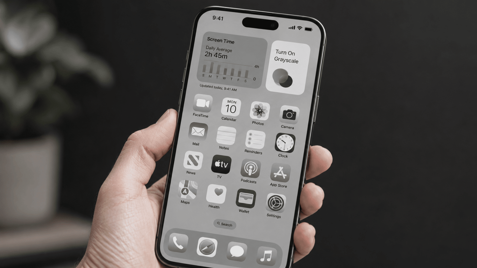 person holding a smartphone with grayscale display showing screen time settings to reduce phone usage habits