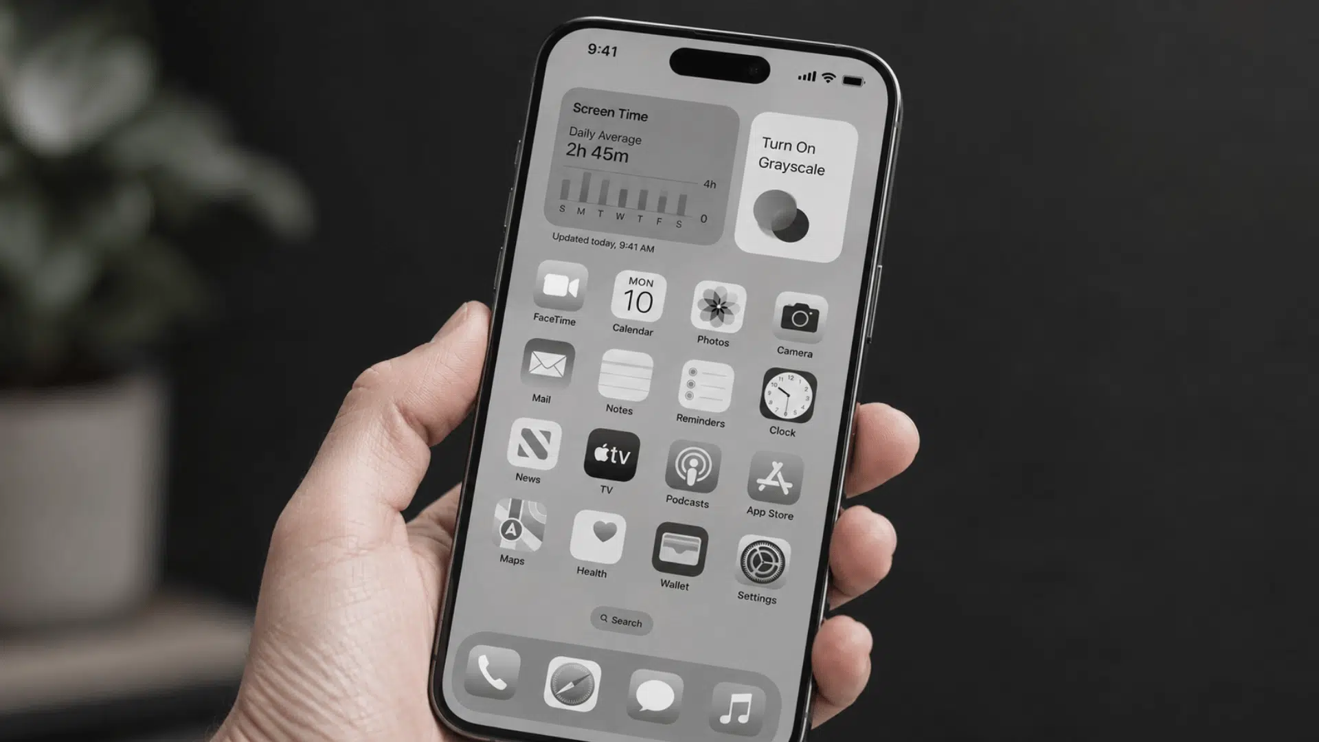 person holding a smartphone with grayscale display showing screen time settings to reduce phone usage habits