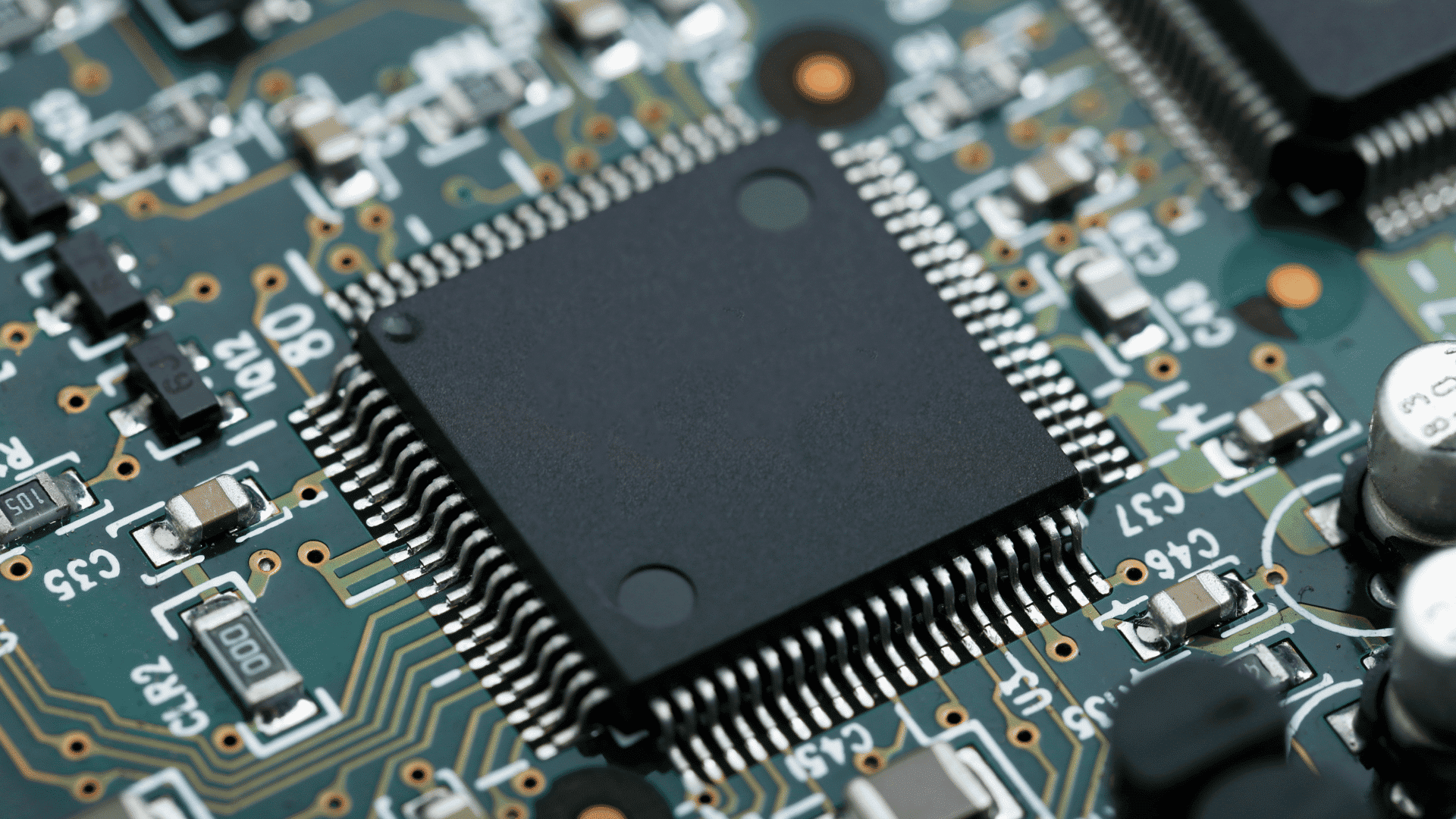 close up of a microchip mounted on a printed circuit board with electronic components and fine conductive traces