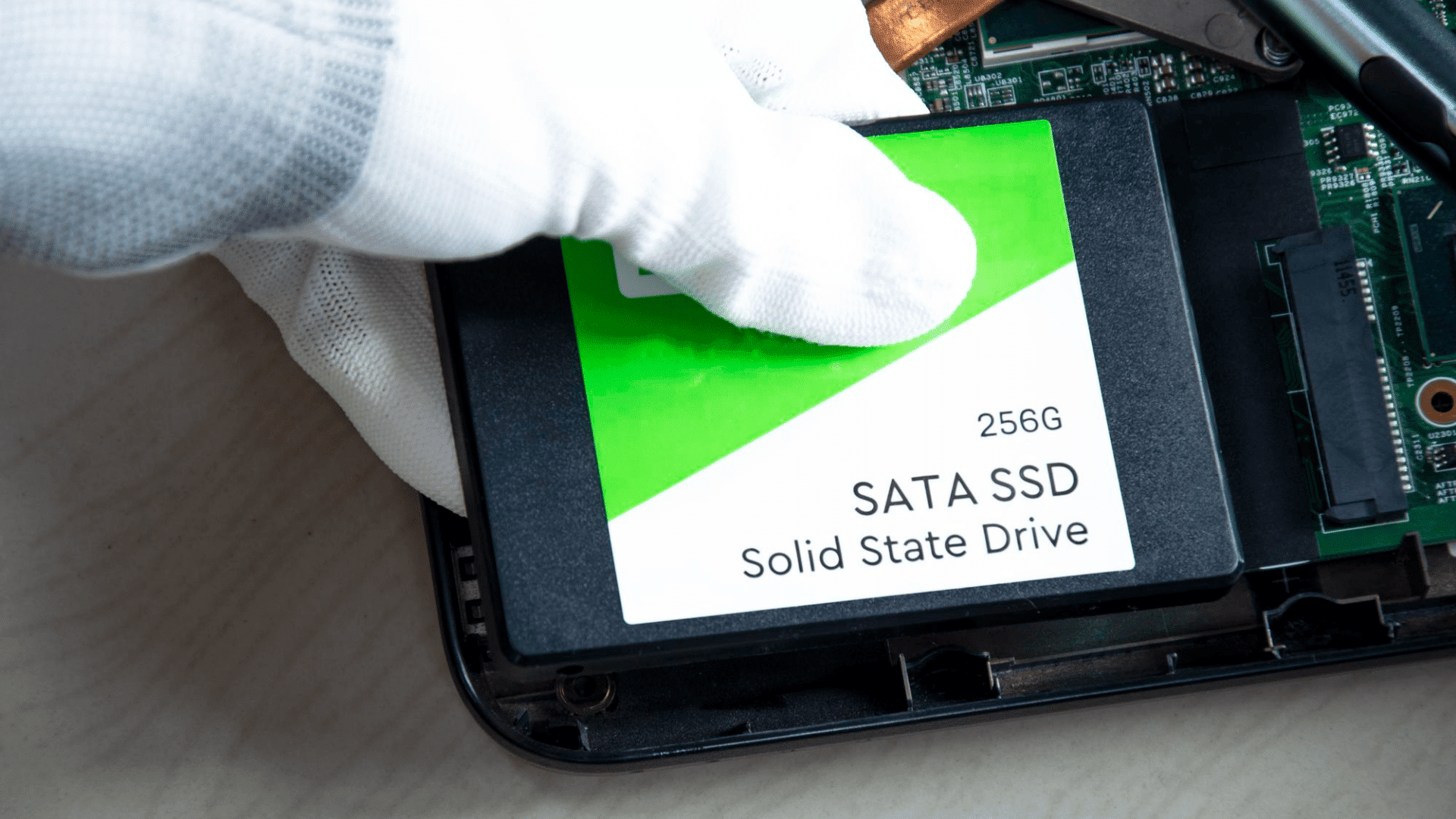 gloved hands installing ssd into a slot in the laptop with two fifty sex gigabytes of memory