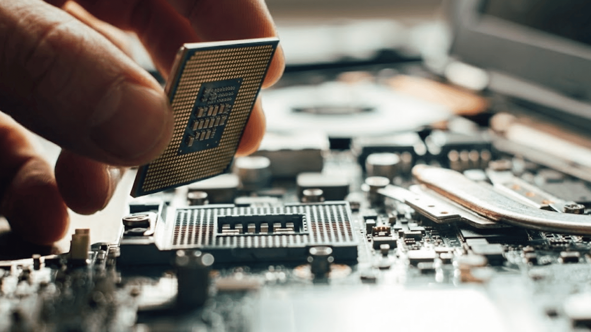 hand holding a computer processor above a motherboard socket during cpu installation inside an open desktop computer system