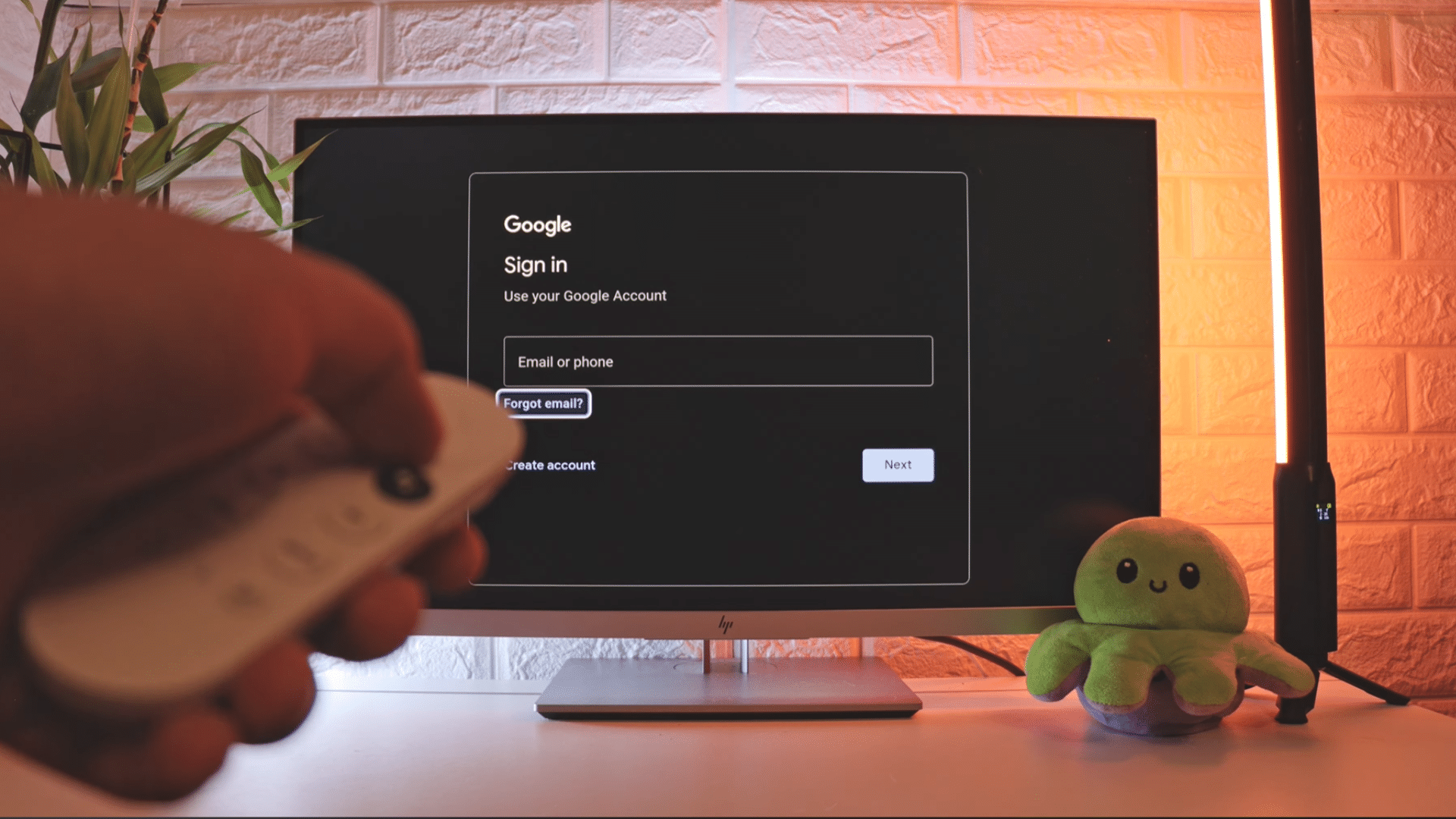 hand holding a remote control while viewing a google account sign in screen on a television during device setup in a warmly lit room