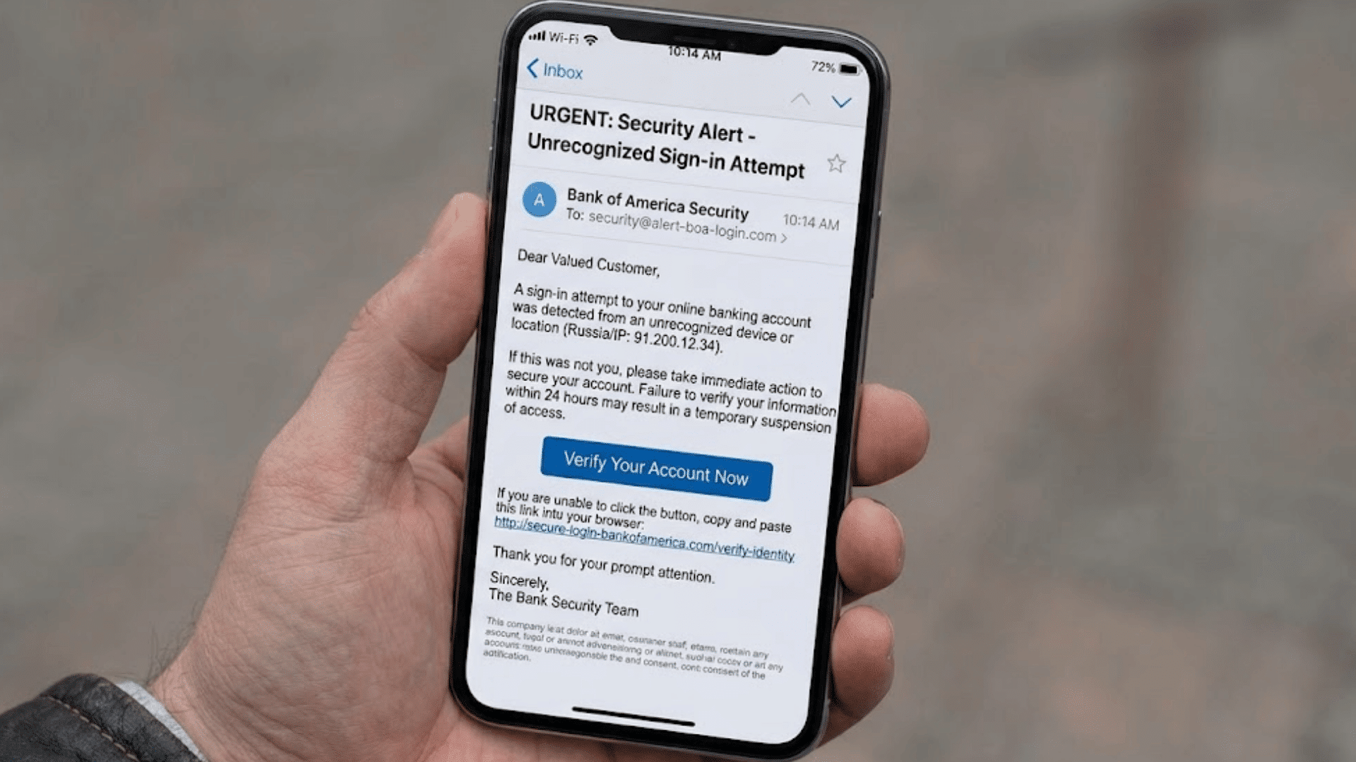 hand holding smartphone displaying fake bank security alert email with verify account button warning of suspicious sign in attempt
