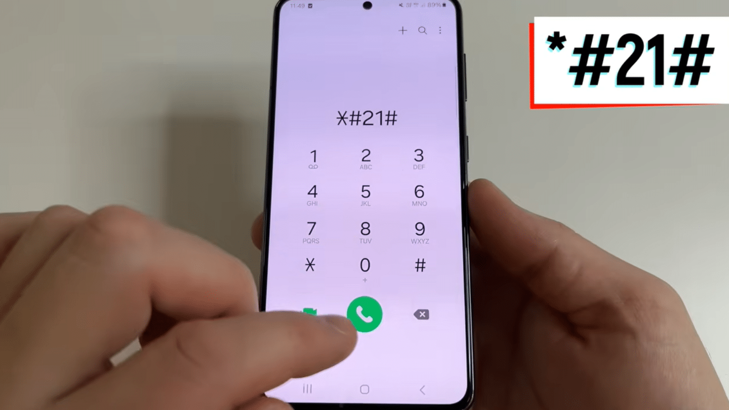 hands holding a smartphone with dial pad open showing star hash 21 hash code and finger pressing call button