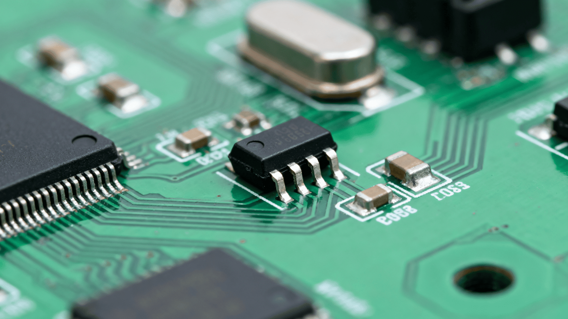 black semiconductor component on green circuit board with detailed electronic pathways and microchip parts