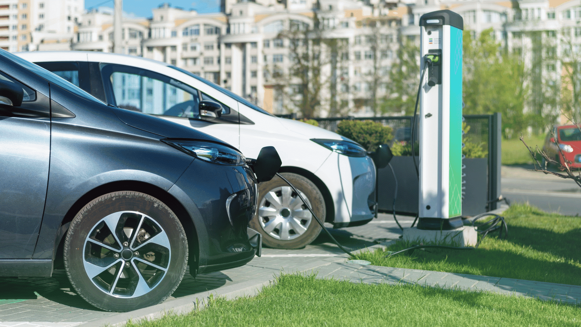 two electric cars plugged into a charging station on a city street