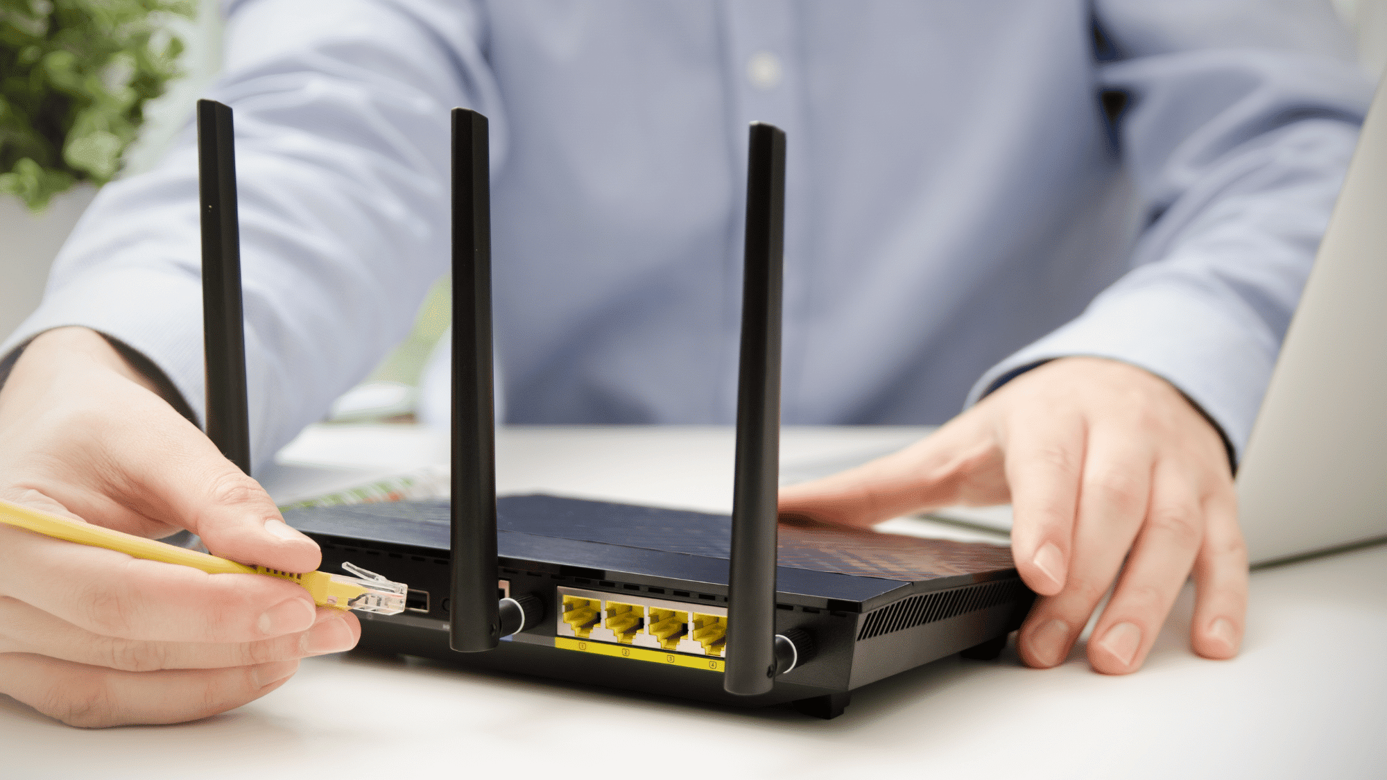 person setting up a wireless router with antennas and ethernet cable for network connection setup