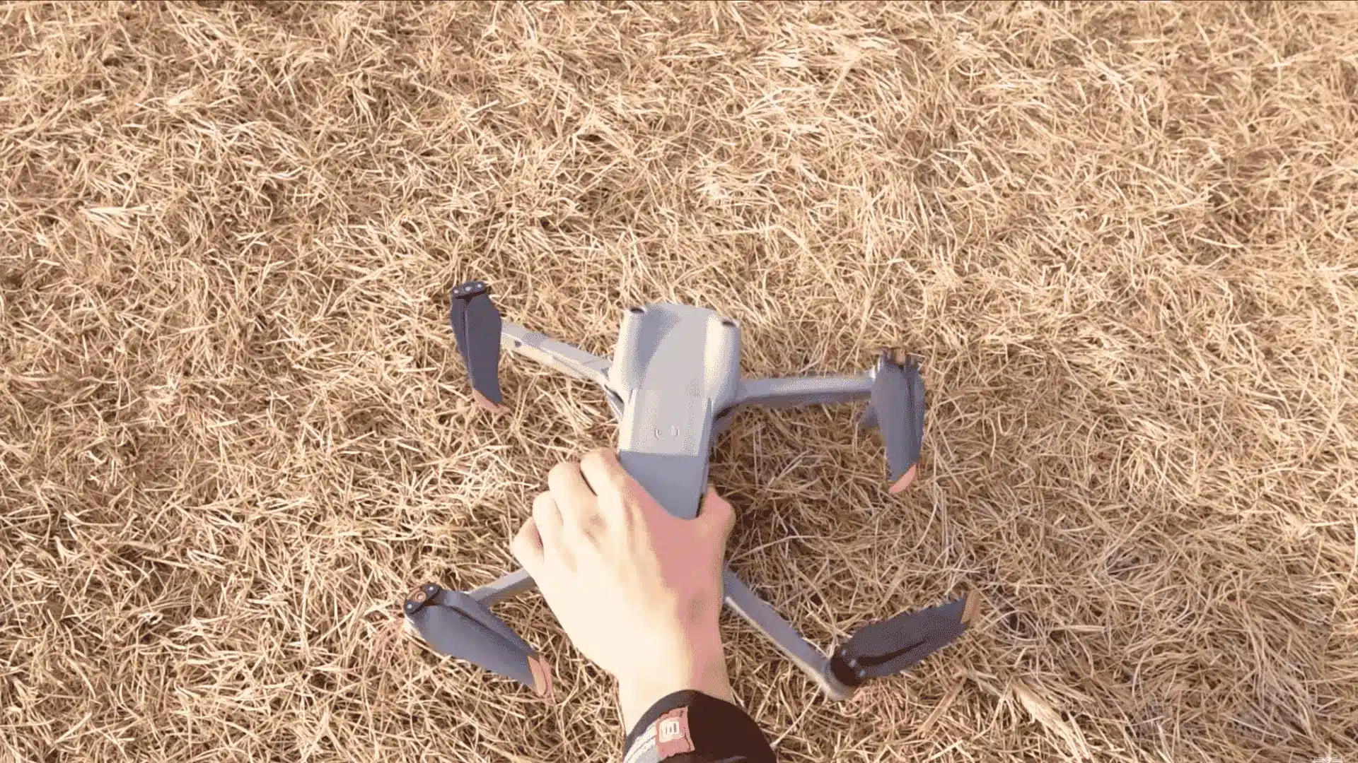 top view of a drone being unfolded and positioned on dry grass before a beginner takeoff