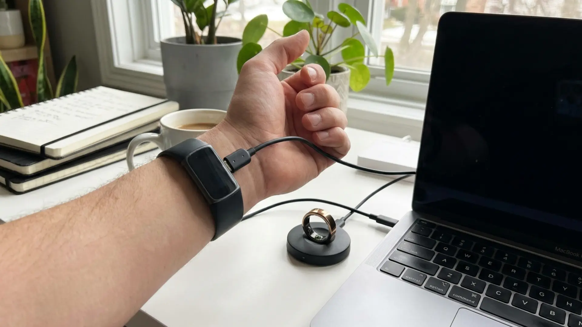 wrist tracker charging while worn beside a smart ring resting on its charging dock nearby