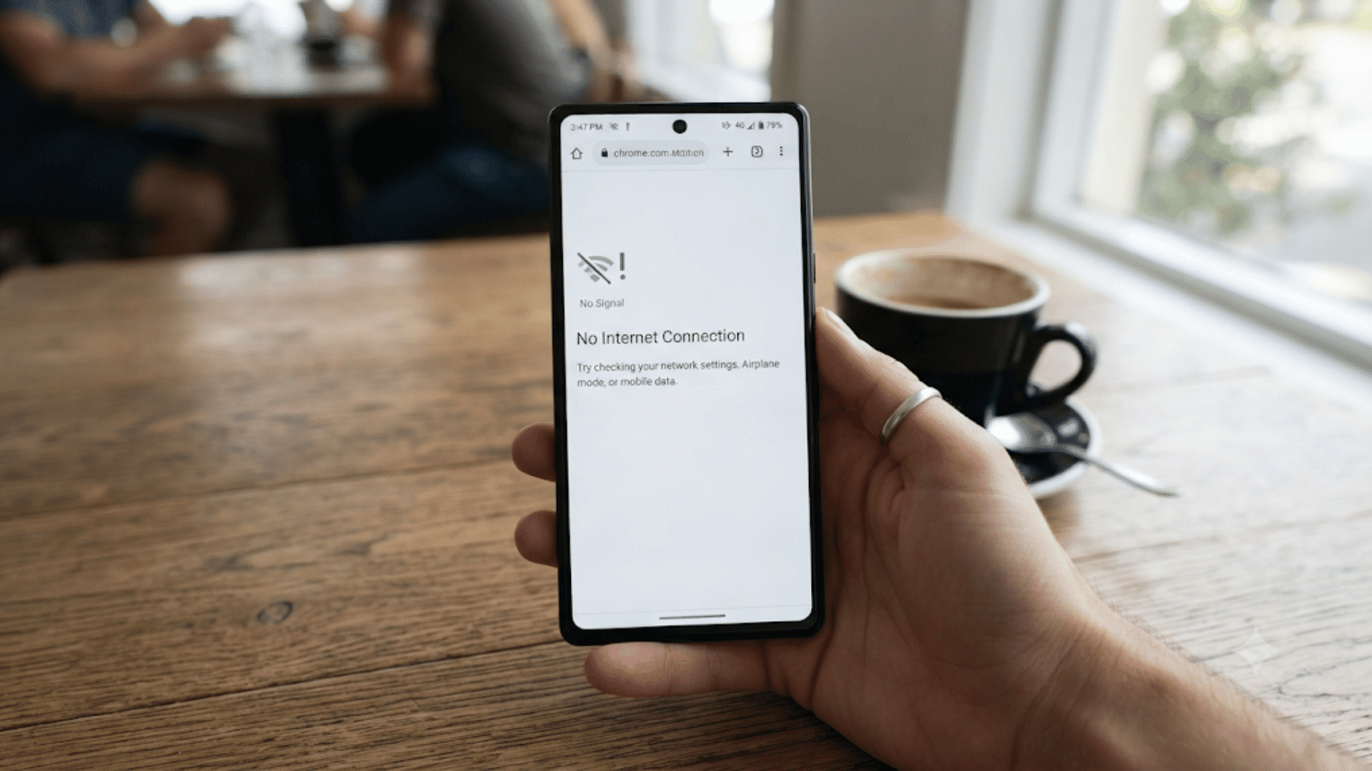 person holding smartphone displaying no internet connection message on screen near window