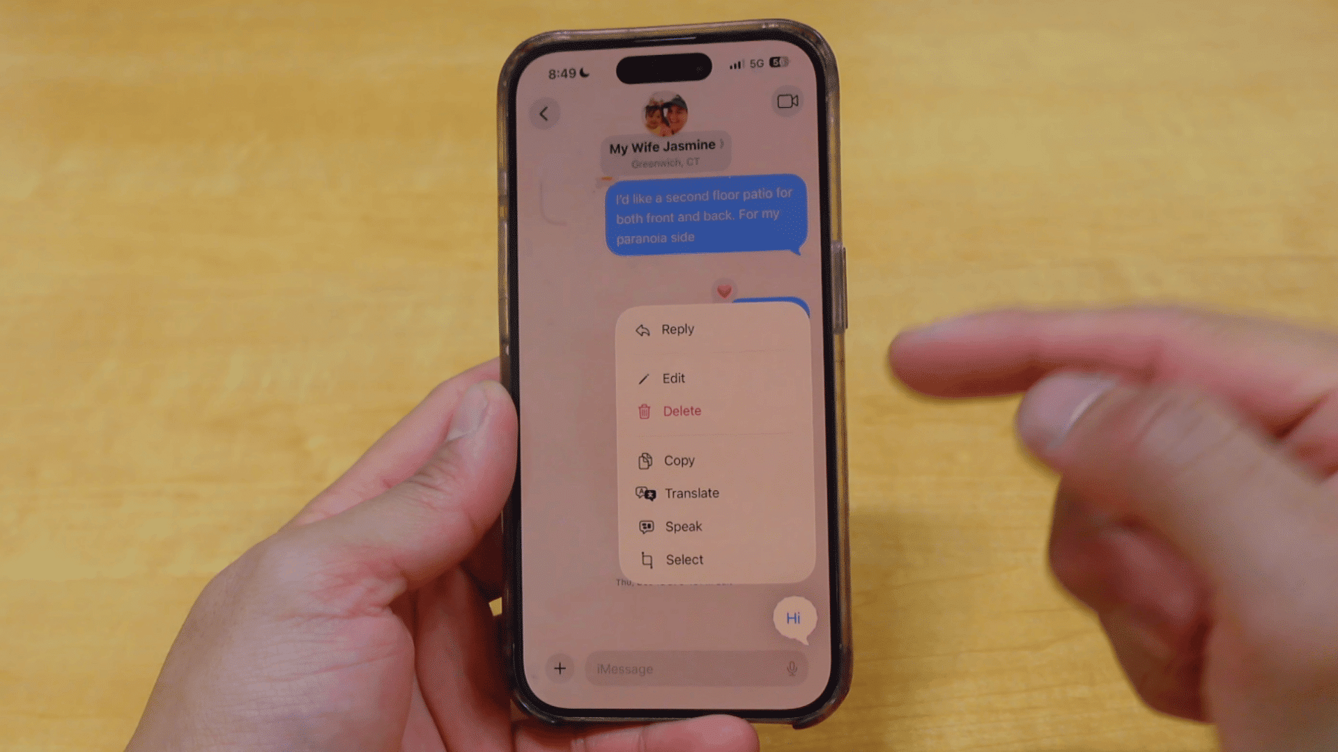 person holding an iphone with the imessage message options menu open after long pressing a text message in a conversation