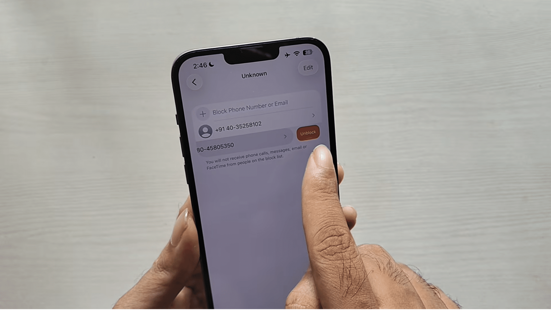iphone blocked contacts screen showing unblock option while managing a blocked phone number list in settings menu